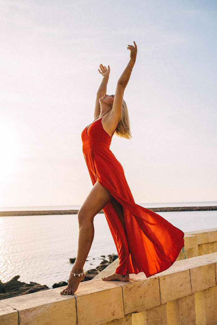A Woman in Red Dress Dancing on a Ledge